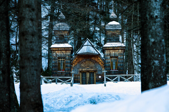 View of the historic Russian Chapel with its traditional wooden architecture and onion domes nestled in a snowy pine forest Slovenia.