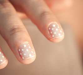 macro detail of female hands with elegant polka dot nail art manicure © Jonathan