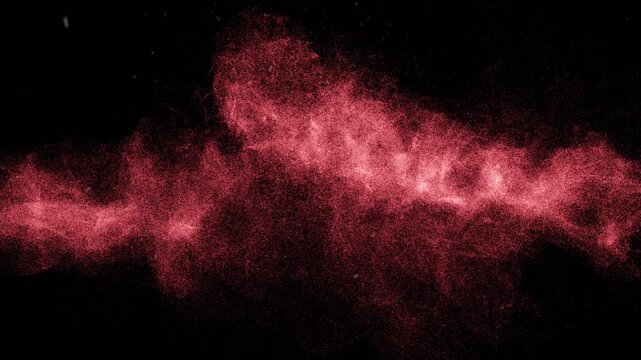 Red particles exploding in a dark space with a black background and small white specks