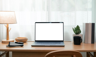 Fototapeta premium Front view of laptop mockup with blank white screen on wooden desk. Clean home office interior with natural light and minimalist decor.