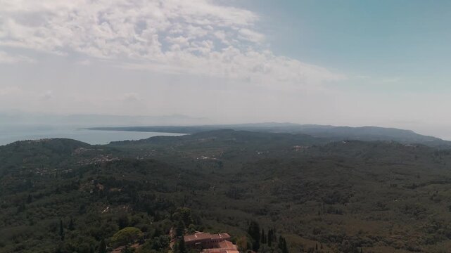 Aerial View Leaving Chlomos Village Over Lush Green Landscape in Southern Corfu, Greece