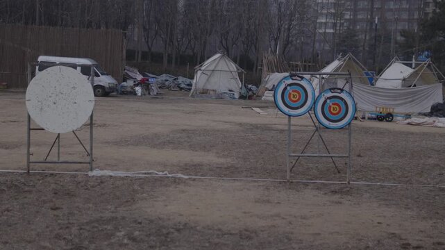 Archery targets standing on practice range, with traditional round white targets and a set of bullseye targets, preparing for a competition in an outdoor setting