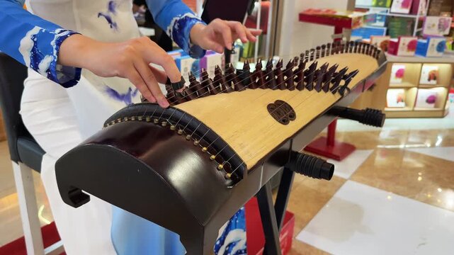 Close up of Woman hands Playing Traditional Vietnamese Dan Tranh Zither at Market Stall