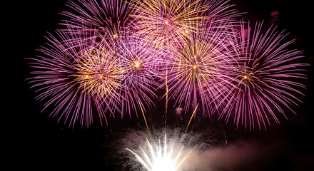 Fototapeta premium Vibrant purple and gold fireworks display exploding in the night sky during a celebration or new years eve event