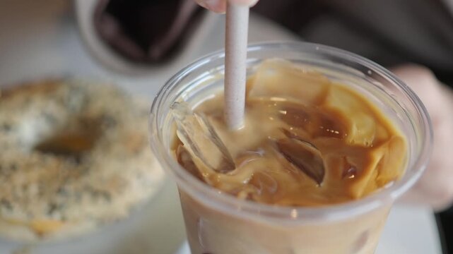 Person stirs iced coffee with a straw at a local cafe