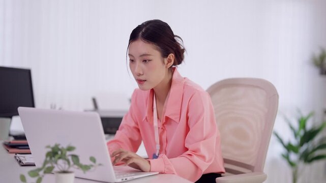 Asian businesswoman professional employee using laptop computer typing working online at modern office desk bright workspace concentrate focus productivity