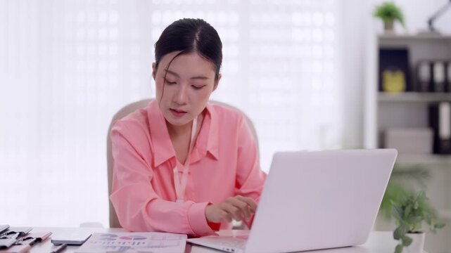 Asian businesswoman professional office worker typing laptop computer working report finance data analysis desk home office modern workspace business casual