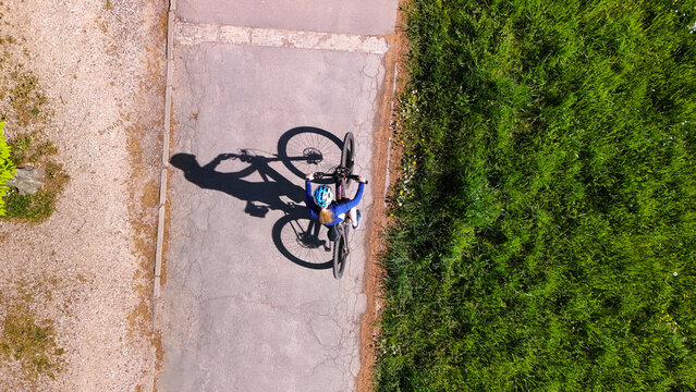 Top View of Woman Cycling on Rural Road with Strong Shadow