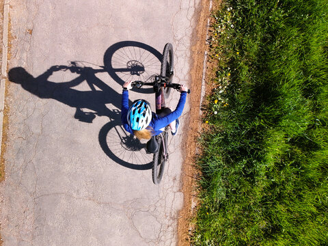 Top View of Woman Cycling on Rural Road with Strong Shadow
