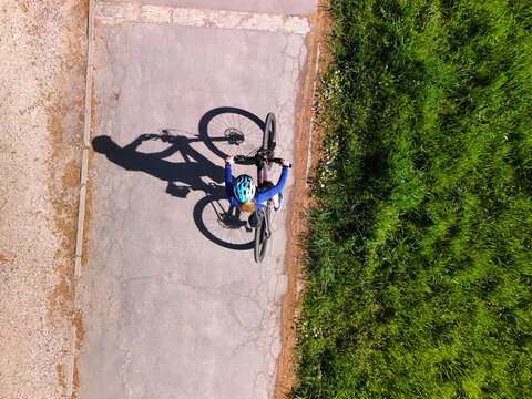 Top View of Woman Cycling on Rural Road with Strong Shadow