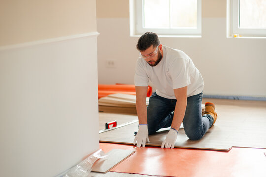Worker installing new laminate flooring planks in building