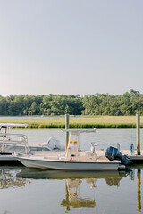 Fototapeta premium Small motorboats moored at a wooden pier in a marsh at sunset