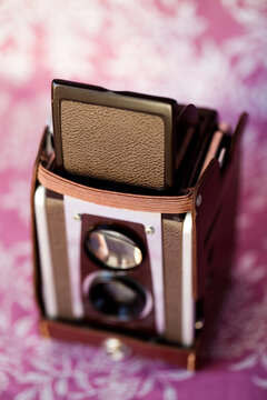 Vintage twin lens reflex style camera leather strap pink background