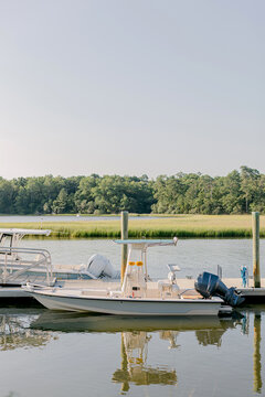 Small motorboats moored at a wooden pier in a marsh at sunset
