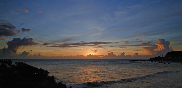 Coastal sunset with golden horizon and gentle ocean waves at twilight