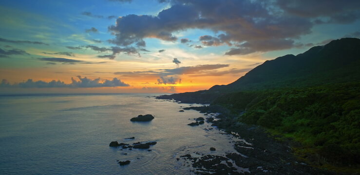 Sunset sky with vibrant orange and purple clouds above a dark ocean