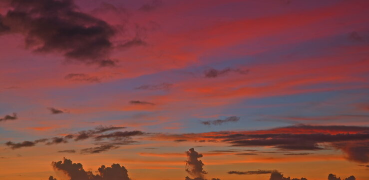 Vibrant pink purple sunset sky with scattered clouds over a calm sea