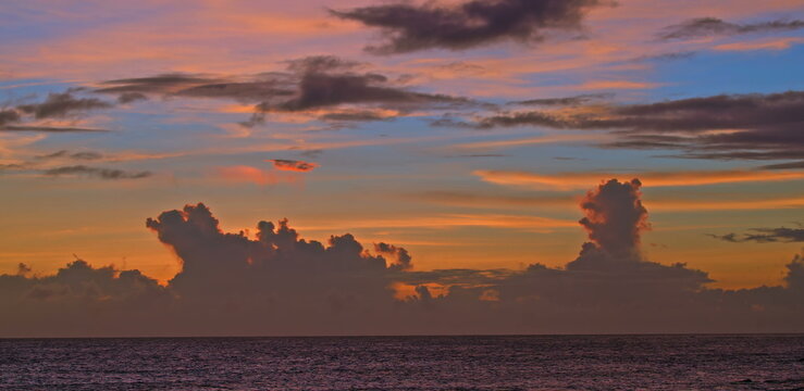 Towering golden cumulus clouds glowing under a colorful twilight sky