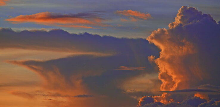 Towering golden cumulus clouds glowing under a colorful twilight sky
