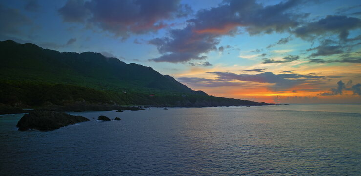 Sunset sky with vibrant orange and purple clouds above a dark ocean