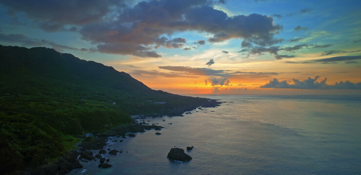 Sunset sky with vibrant orange and purple clouds above a dark ocean