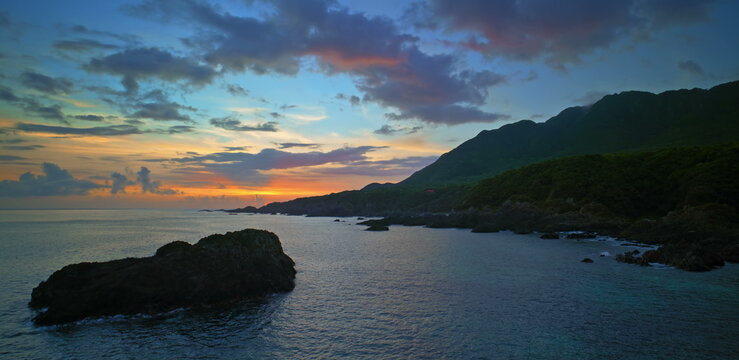 Sunset sky with vibrant orange and purple clouds above a dark ocean