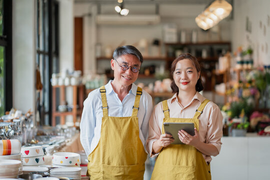 Father and daughter Asian small business owners standing in their shop