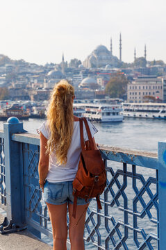woman traveler on galata bridge looking at suleymaniye mosque in istanbul