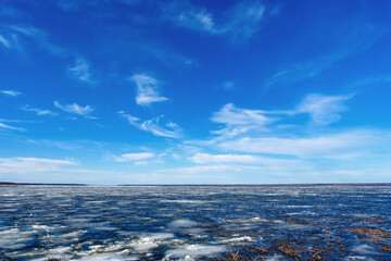 Frozen river with drifting ice under blue sky with clouds winter landscape natural water surface cold season scenic background environment © Dmitrii Masquerade