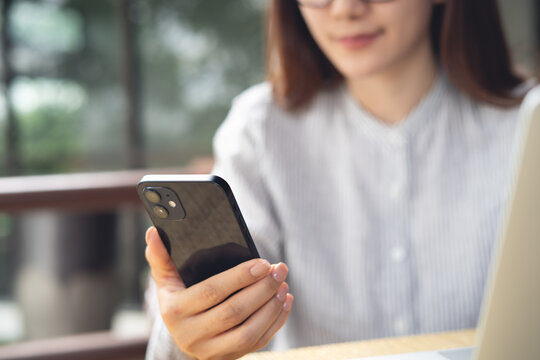 Woman using smartphone with laptop on table at outdoor cafe, surfing the net, remote work, online business 