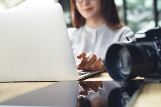Content creator, photographer working on laptop with DSLR camera on table, close up
