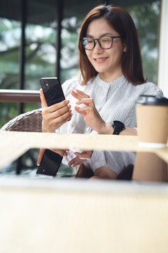 Smiling woman using smartphone at outdoor cafe during working remotely, online business, digital nomad lifestyle, vertical
