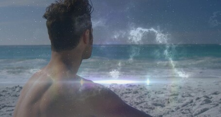Sitting shirtless man watching ocean at sandy shoreline, with lens flare and nebula overlay © vectorfusionart
