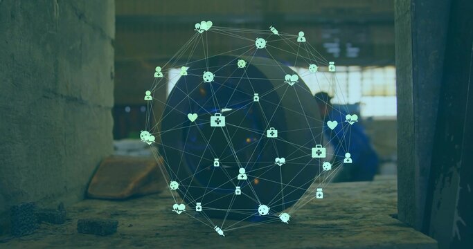 Hovering holographic network sphere projecting icons over tire in workshop, blue-coveralls worker