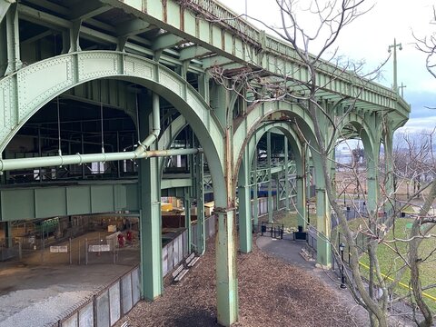 View of the weathered green steel arches of an elevated viaduct with bare winter trees and a park walkway below New York, New York, United States.