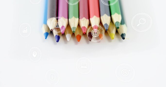 Displaying eleven sharpened colored pencils with tips down on white sheet, showing faint icons
