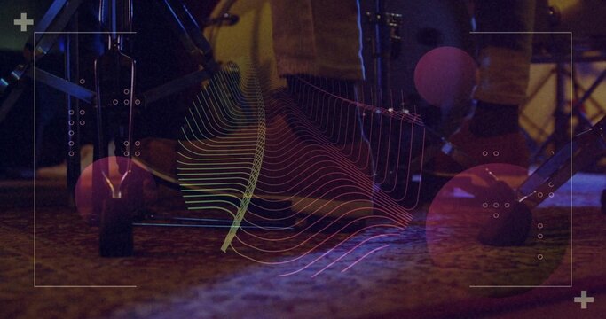 Glowing drum kit showing rubber-capped spurs, pedal axle and cables on carpeted stage with overlay