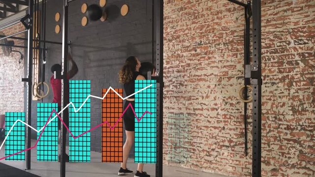 Two partners doing wall-ball throws in fitness gym, squat drive causing live charts for tracking