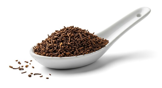 A close-up view of a white ceramic spoon filled with granulated ctc tea leaves on a clean white background, representing traditional tea processing.