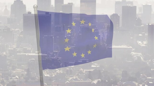 European Union flag fluttering and folding on pole with gusts animating fabric against hazy skyline