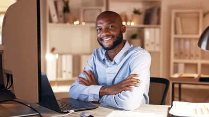 Obraz premium Businessman, arms crossed and smile with laptop in office, portrait and working late for investment. Night, actuary and black person with tech for risk assessment, happy or pride for project in Kenya