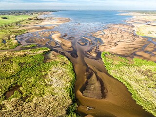 Malownicze ujęcie z góry na deltę rzeki i piaszczyste mielizny. Widowiskowy krajobraz naturalny z lotu ptaka, ukazujący błękitną wodę, zielone brzegi i ujście rzeki. Idealne do tematów ekologii. © Henryk Niestrój