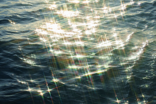 Bright sunlight shimmering on ocean surface with sparkling reflections