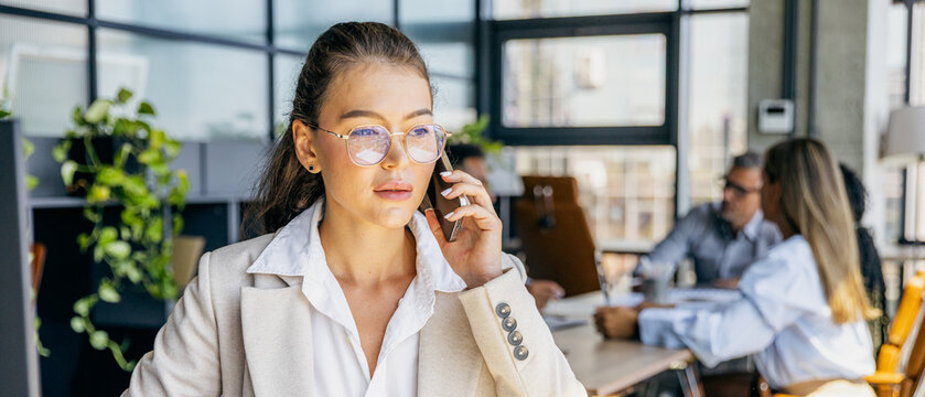 Employee professionally speaking on phone amidst team collaboration scene