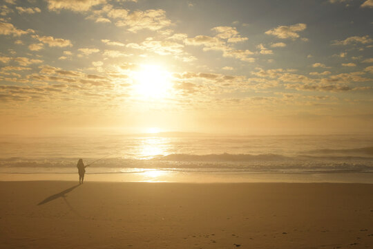 Side view teenage girl fishing on beach at sunrise Outer Banks N