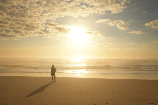 Behind teen girl fishing on beach at sunrise Cape Hatteras Natio