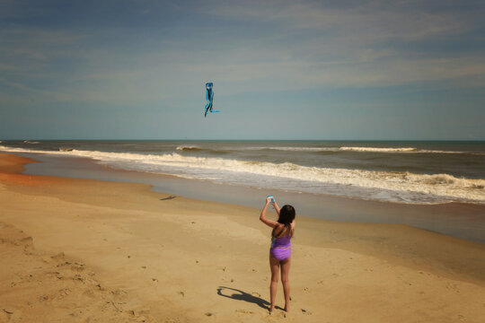Above young girl flying kite sunny beach Cape Hatteras National