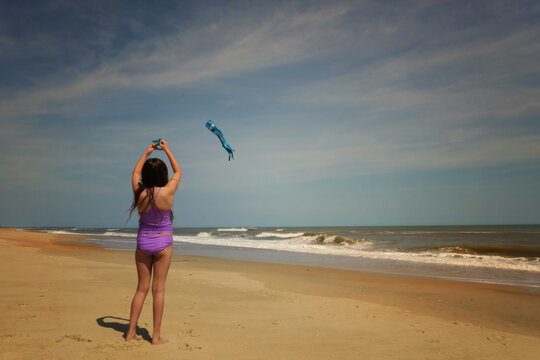 Young girl flying blue kite on sunny beach Outer Banks North Car