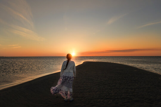 Behind tween girl walking towards beautiful beach sunset Pamlico