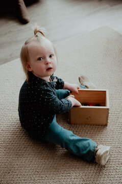 Toddler girl sitting on floor with box of toys